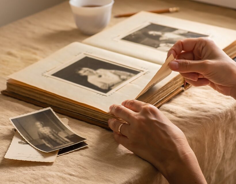 Hands turning the page of an archival album of letters and photographs