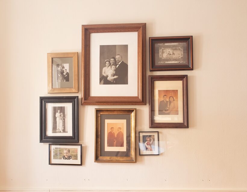 A hand-hung gallery wall of small framed family photographs across decades