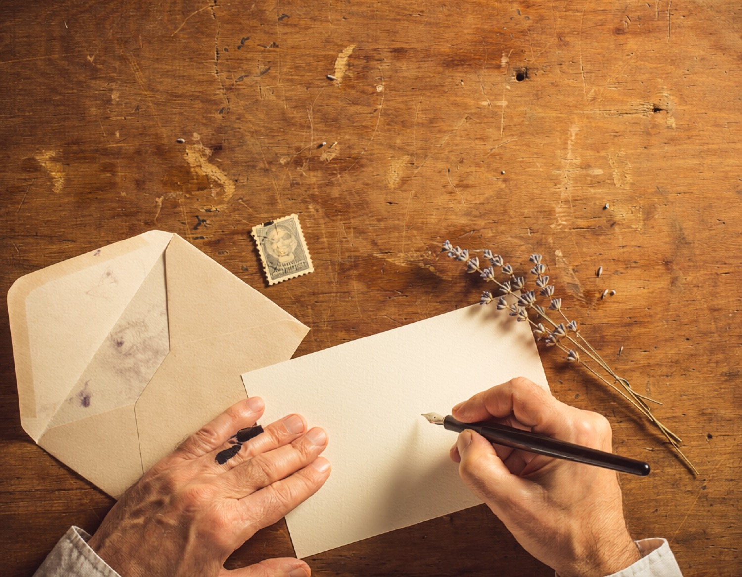 A hand writing a card by a sunlit window